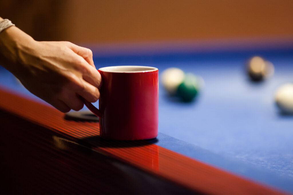 Coffee cup on pool table edge